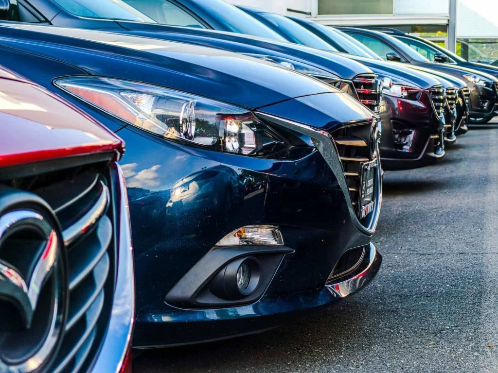 close up shot of various brands of cars front bumpers lined up at a second hand  car yard